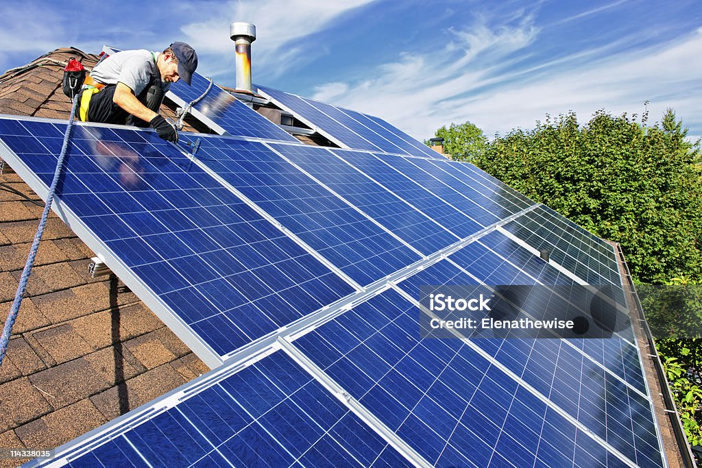 Solar panel installation Man installing alternative energy photovoltaic solar panels on roof Solar Panel Stock Photo