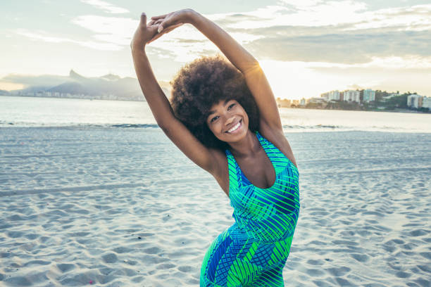 istock smiling fit young woman stretching on the beach 1143385584