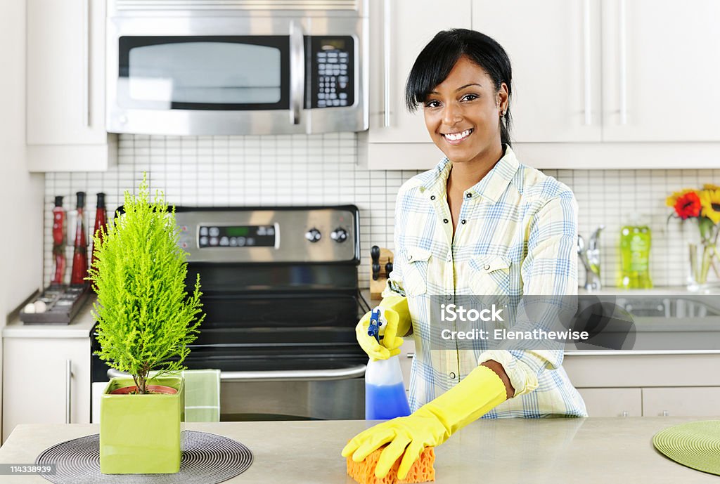 Young woman cleaning kitchen Smiling young black woman with sponge and rubber gloves cleaning kitchen African Ethnicity Stock Photo