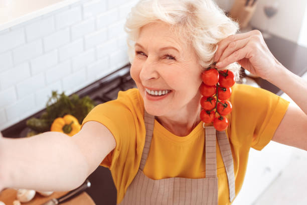 istock Grandma making selfie with tomatoes. Tomatoes are like earrings 1143389929