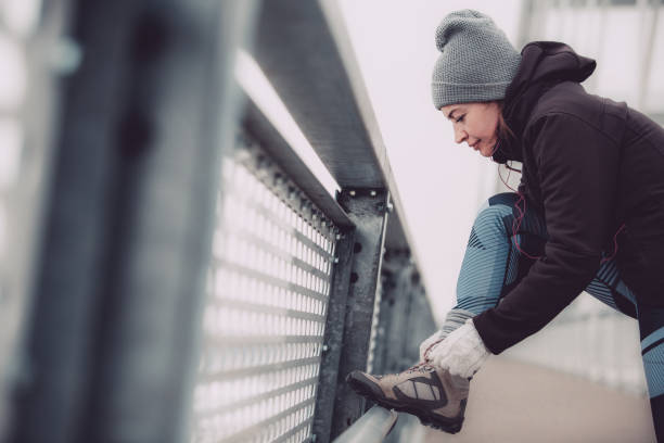 Copy space shot of a female runner tying shoelace on a bridge railing.