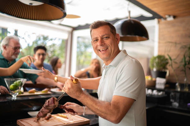 Portrait of man cutting picanha meat during barbecue Portrait of man cutting picanha meat during barbecue barbecue social gathering photos stock pictures, royalty-free photos & images