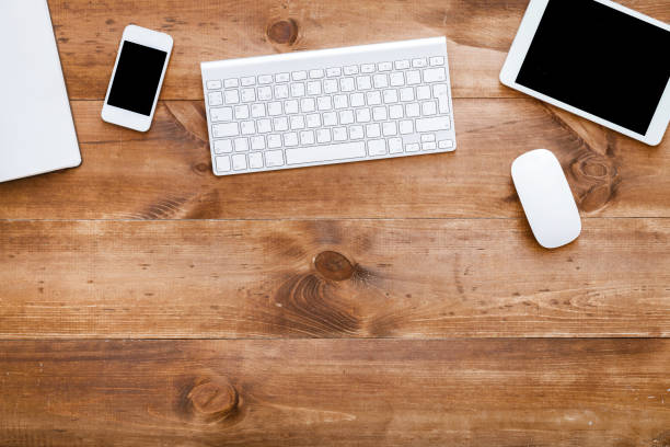 istock Business devices on brown wooden desk, computer keyboard with phone, mouse and digital pc tablet modern gadgets on office table desktop workspace, workplace background, top view from above copy space 1143391265