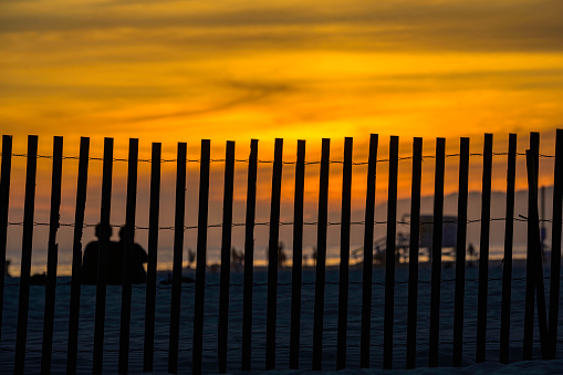 Beautiful sunset on the beach with silhouette people watching sunset behind the wood fence