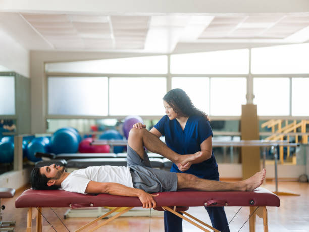 istock Physical therapist stretching patient's leg on massage table 1143400898