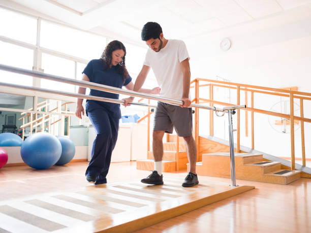 männlicher patient gibt kleine schritte in parallelen bars - scrubs professional sport indoors healthcare and medicine stock-fotos und bilder