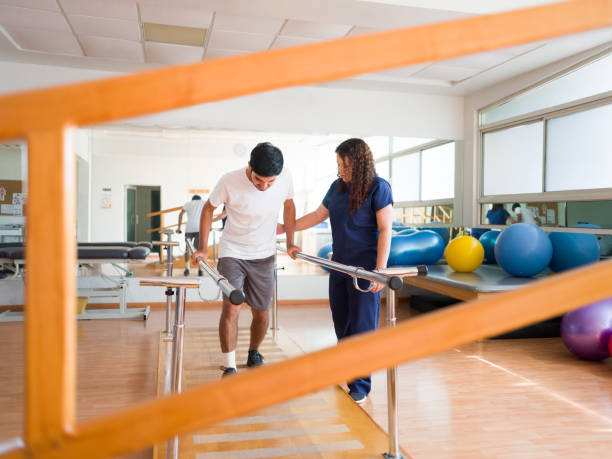 istock Latin male patient walking in parallel bars with therapist 1143400949