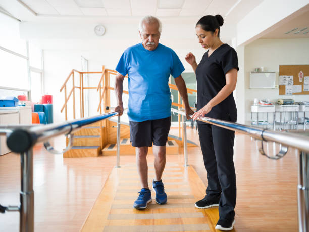 senior man giving steps in parallel bars - senior adult hospital uniform gray hair imagens e fotografias de stock