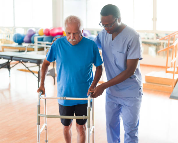 istock Senior man walking with support next to nurse 1143401069