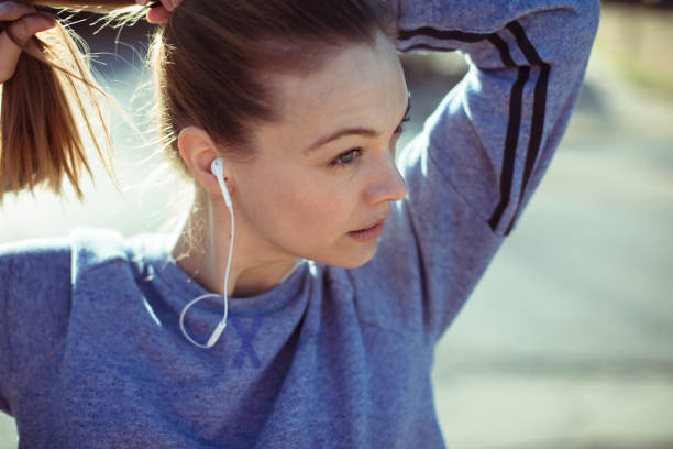 Getting Ready Close up of a woman tying her hair before jogging woman tying hair in ponytail getting ready for exercising stock pictures, royalty-free photos & images