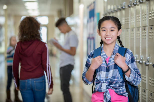 istock Happy female Junior High student standing by lockers 1143416842