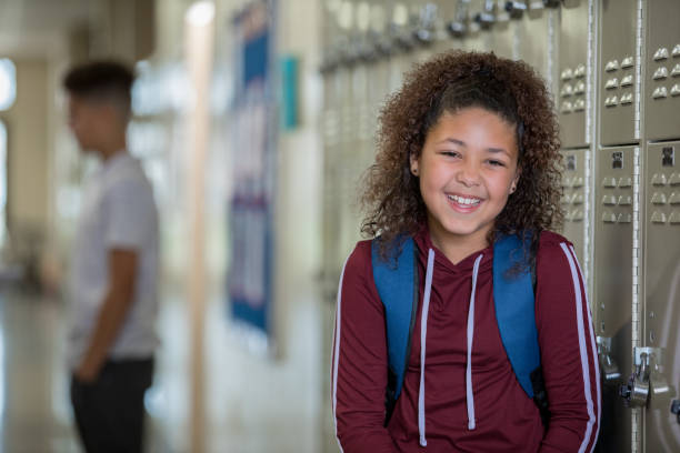istock Female middle school student smiling beside lockers 1143416848
