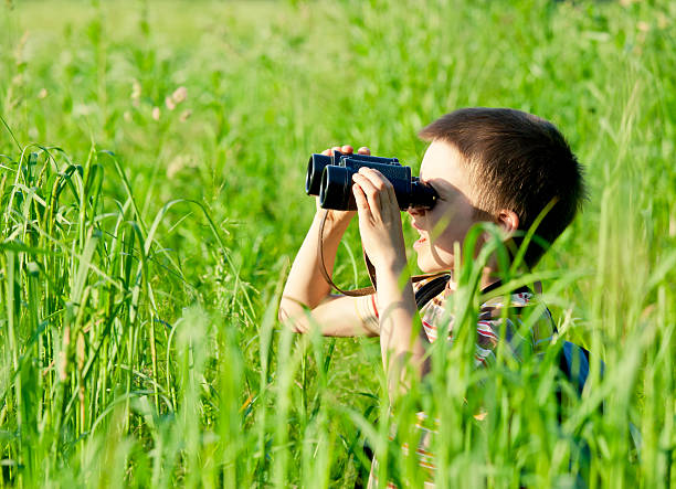 istock Young boy standing in tall green grass with binoculars 114341888