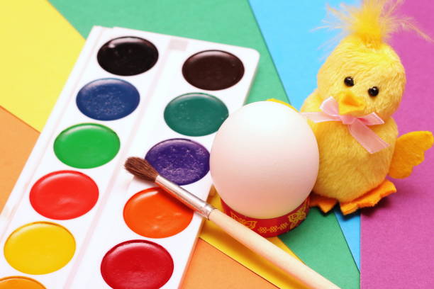 счастливой пасхи. курица-желтая игрушка с кистью готовится раскрасить белокое куриное яйцо акварелью. - baby chicken eggs young bird easter стоковые фото и изображения