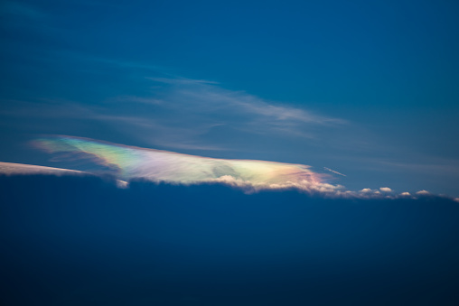 Beautiful abstract iridescence cloud irisation or rainbow cloud shining out from behind the cloud on sunset time
