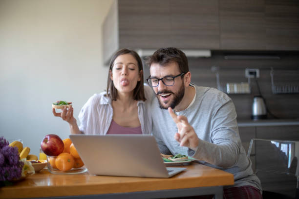 istock Young couple with vegan breakfast in dining room and computer having web call 1143429895