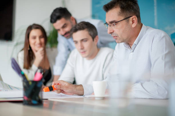 istock Man pointing with highlighter to data on chart, colleagues listening 1143431096