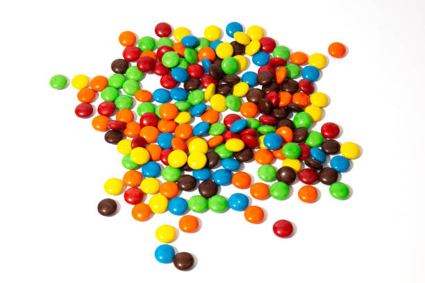colorful chocolate m&ms in and out of focus on white background - candy coated imagens e fotografias de stock