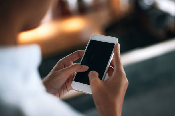 istock Woman using a smartphone read and text messages with blank space screen display from behind view- woman office worker- digital and communication concept 1143436693