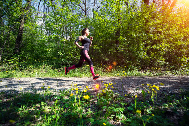 eine junge frau, die im waldfußweg lief. - running track women running spring stock-fotos und bilder