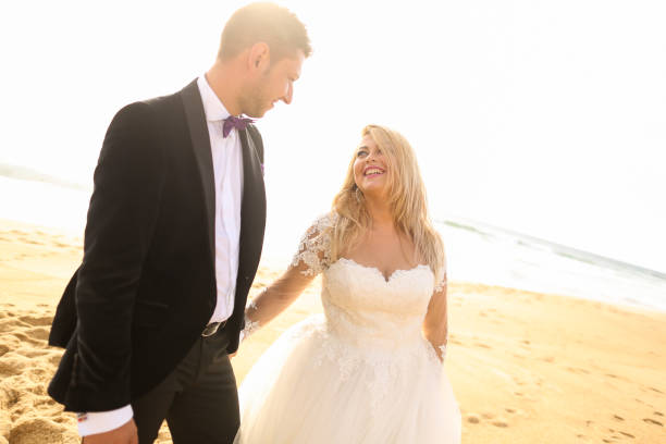 istock Happy blonde bride and handsome groom posing on beach 1143440882