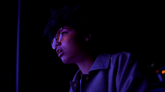 Amazed afro-american girl in eyeglasses watching movie at open-space cinema