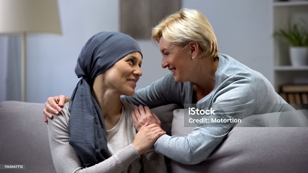 Mom supporting and hugging her daughter with cancer, visits in oncohospital Patient Stock Photo