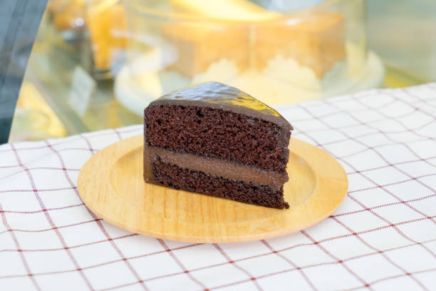 Piece of delicious chocolate cake on wooden plate stock photo