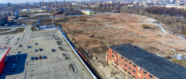 Aerial view of the wasteland, hypermarket parking and modern buildings on the site of the destroyed Onego Tractor Plant in the center of Petrozavodsk