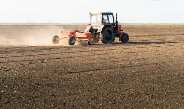 istock Farmer with tractor seeding  crops at agricultural field 1143459147