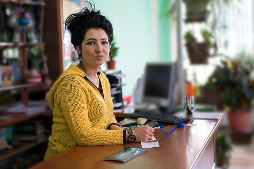 Portrait of young and beautiful local business women at desk in Karakol with PC and  blurred background, Kyrgyzstan