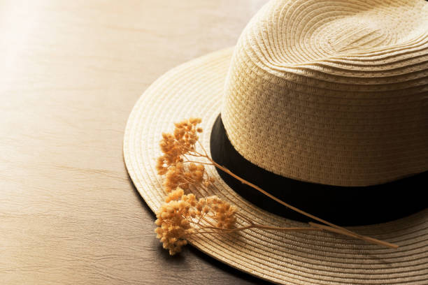 white black hat with small dried flower on soft orange brown cozy sunlight summer background