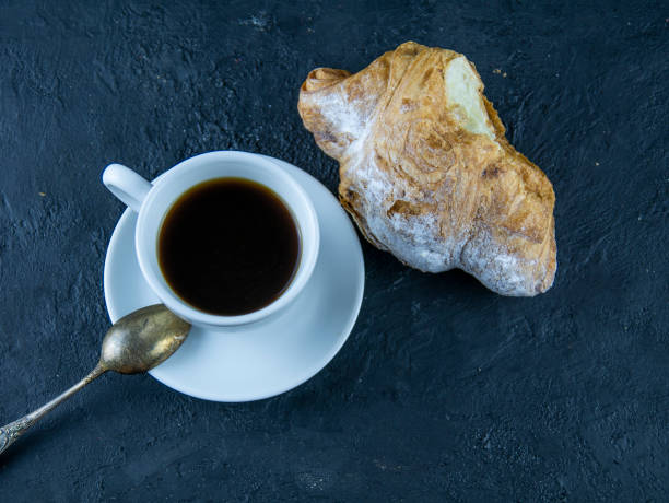 istock Sweet buns and cup of coffee on a dark stone background 1143463680