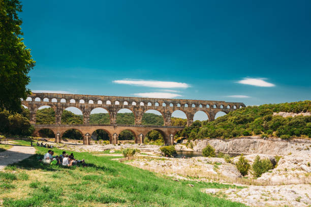 personas descansando cerca del antiguo acueducto romano de pont du gard, nimes, francia - aqueduct roman ancient rome pont du gard fotografías e imágenes de stock