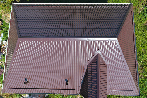 The roof of corrugated sheet. Roofing of metal profile wavy shape. A view from above on the roof of the house.