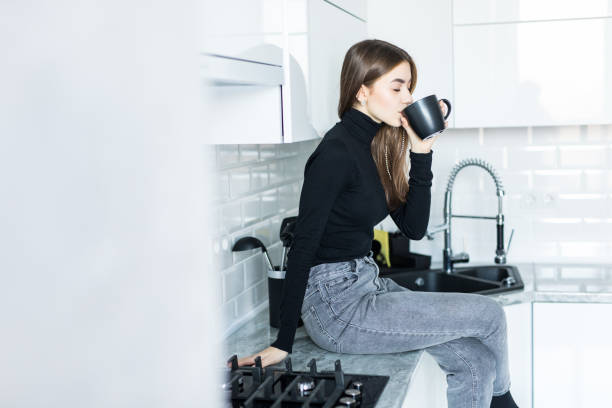 istock Beautiful young girl in home clothes smiling while sitting in kitchen 1143468064