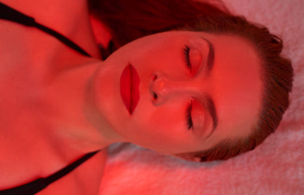 time for relaxation portrait of woman relaxing with her eyes closed at infrared lights. light therapy stock pictures, royalty-free photos & images