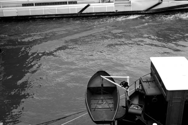 Paris, France - April 06, 2019. A small boat tied to a rope, waiting to be lowered into the river water. Black and white photos.