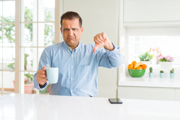 Middle age business man drinking coffee in the morning at home with angry face, negative sign showing dislike with thumbs down, rejection concept Middle age business man drinking coffee in the morning at home with angry face, negative sign showing dislike with thumbs down, rejection concept bad coffee stock pictures, royalty-free photos & images