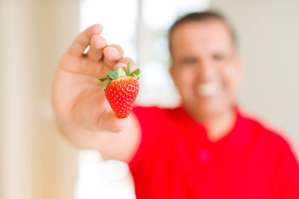 Close up middle age man holding strawberry