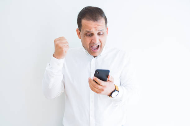 istock Middle age man using smartphone over white wall screaming proud and celebrating victory and success very excited, cheering emotion 1143478146