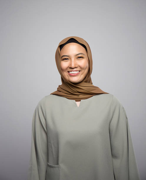 istock young muslim woman smiling at camera isolated on grey 1143478995