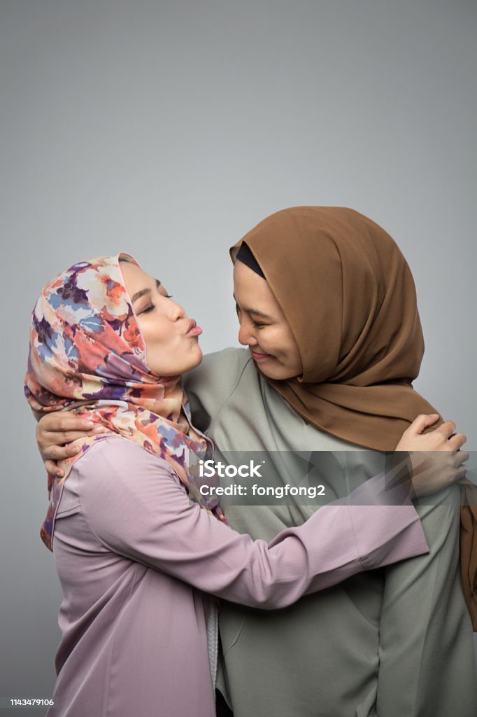 Portrait of attractive two young muslim girl having fun together isolated on grey background Adult Stock Photo