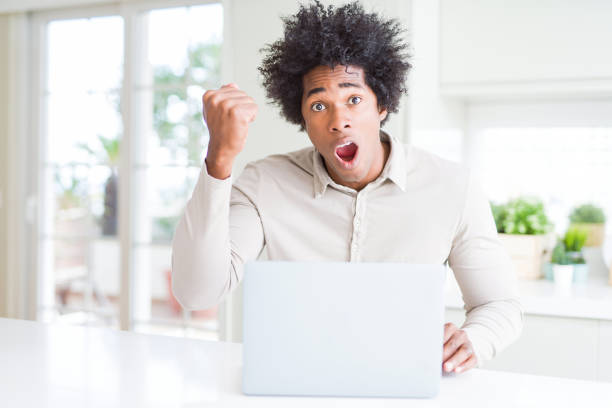 istock African American man working using laptop annoyed and frustrated shouting with anger, crazy and yelling with raised hand, anger concept 1143480525