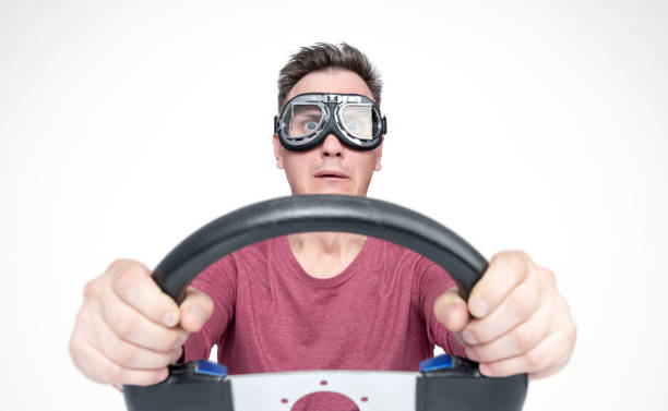 istock Scared man with open mouth in stylish goggles with steering wheel, car driver concept. Front view. 1143481056