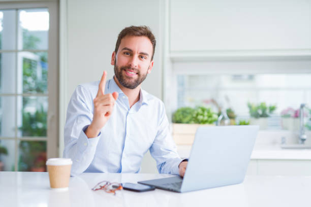 istock Handsome man working using computer laptop and drinking a cup of coffee very happy pointing with hand and finger to the side 1143482312