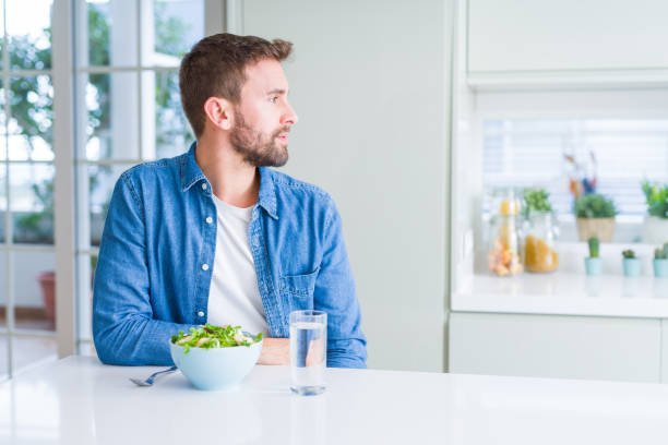 istock Handsome man eating fresh healthy salad looking to side, relax profile pose with natural face with confident smile. 1143482449