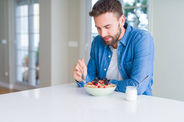 istock Handsome man having breakfast eating cereals at home and smiling 1143482571