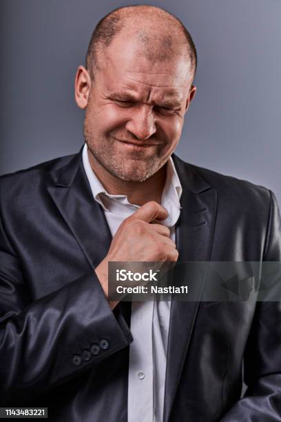 Unhappy Stressed Bald Angry Business Man Pulling The Shirt Collar With Very Bad Emotions In Office Suit On Grey Studio Background Closeup Stock Photo - Download Image Now