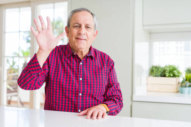 istock Handsome senior man at home showing and pointing up with fingers number five while smiling confident and happy. 1143483905